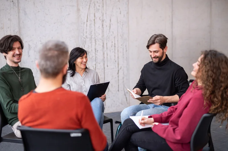 happy-men-and-women-sitting-in-circle-during-group-2023-11-27-05-36-36-utc